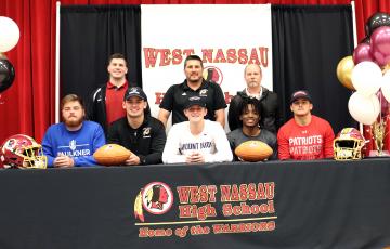 West Nassau football coaches join, from left,  Bryce Morris, Elijah  Canode, Chaz Hirschman,  Zorian Stanton and Bry-son Williams at their college signing celebration Feb. 26. 