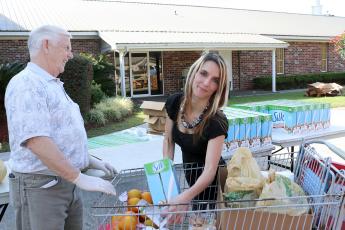 Katie Crane receives items from Gary Norris as residents line up to collect fruit, meat and other goods from a Farm Share food distribution at Hilliard’s Buford Grove Baptist Church March 18. 