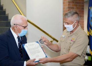 Rear Adm. John Spencer, commander, Submarine Group 10, presents Chief Fire Control Technician Richard Henry (retired) with a flag, letter and coin in celebration of his 100th birthday on behalf of Master Chief Petty Officer of the Navy Russell Smith.  SUBMITTED