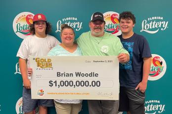 Brian Woodle poses for a photo with his family after winning $880,000 from the Florida Lottery with a Gold Rush Supreme scratch-off ticket.