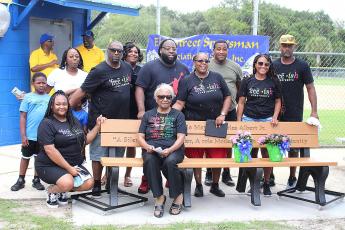 Charles L. Albert Jr.’s family, including wife Ernie, seated, are pictured with the bench honoring Albert at Elm Street Little League.