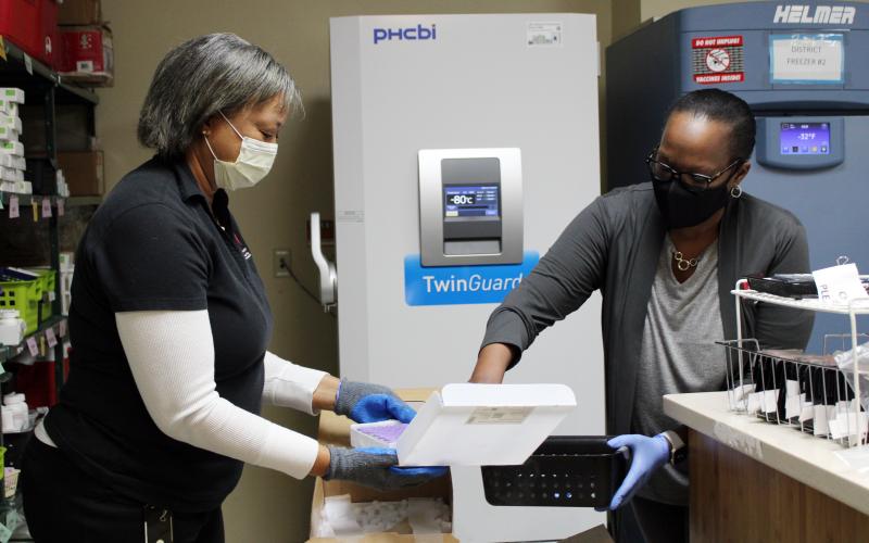 Coastal Health District Laboratory Director Lisa Harris (left) and Chatham County nurse manager Tammi Brown unpack the first doses of the Pfizer COVID-19 vaccine delivered to the district this week. The first vaccines will go to health care providers, first responders and people who work or live in long-term care facilities.