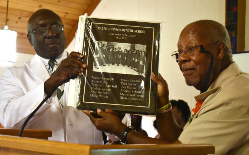 Tommie Mitchell, right, a member of the Ralph Johnson Bunche High School class of 1952, presents a plaque of the graduating class to Artie Jones, president of the high school and Camden County Training School alumni association.