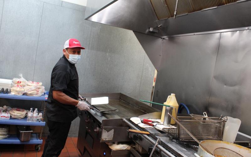 Jose Hernandez works the grill at Pepper’s Cocina Mexicana on Centre Street. The restaurant is working with a smaller staff, as are many across the state, making for longer waits, closed sections and even shorter of hours of operation for some establishments.