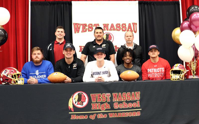 West Nassau football coaches join, from left,  Bryce Morris, Elijah  Canode, Chaz Hirschman,  Zorian Stanton and Bry-son Williams at their college signing celebration Feb. 26. 