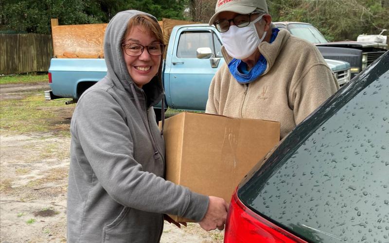 Barnabas volunteer Robert Simoneau delivers an Amelia Fresh box to a Barnabas client. The Amelia Fresh boxes include a variety of locally produced items.