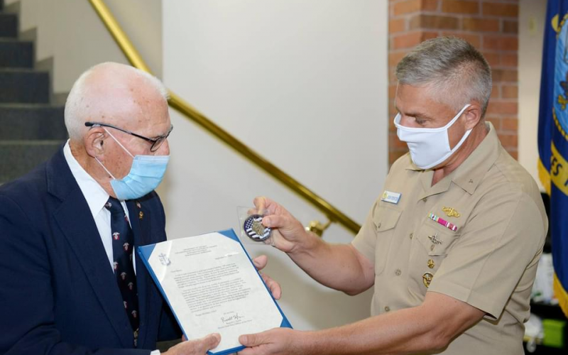 Rear Adm. John Spencer, commander, Submarine Group 10, presents Chief Fire Control Technician Richard Henry (retired) with a flag, letter and coin in celebration of his 100th birthday on behalf of Master Chief Petty Officer of the Navy Russell Smith.  SUBMITTED