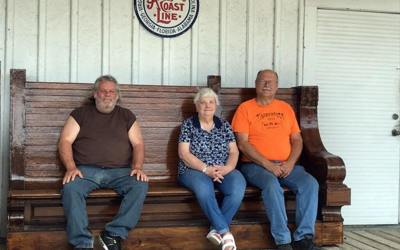 West Nassau Historical Society members Jerry Peterson, from left, Emily Baumgartner and John Hendricks take a break at the Callahan Depot on one of two restored benches that were once part of the Jacksonville Union Terminal waiting area in 1919. Dorothy Higginbotham donated the benches. 