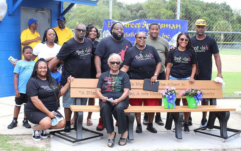 Charles L. Albert Jr.’s family, including wife Ernie, seated, are pictured with the bench honoring Albert at Elm Street Little League.
